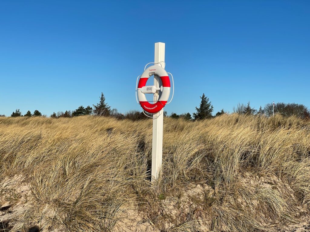 a red and white sign sitting in the middle of a field