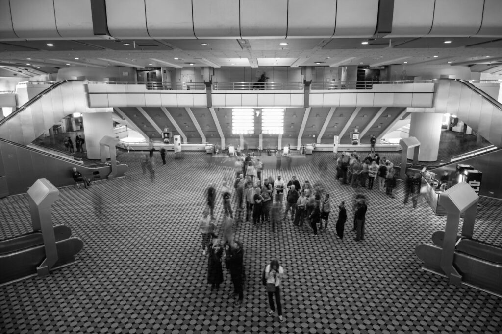 People gathered in a large, modern atrium with escalators.